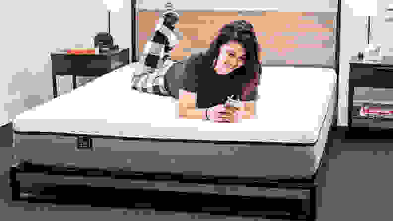 A person on their phone lying on a Lull Original mattress