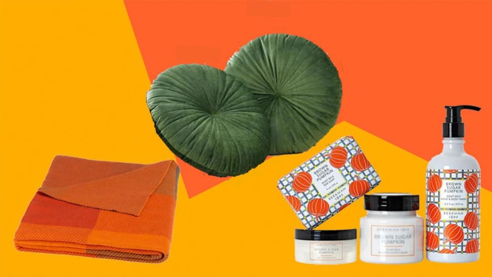 Several fall items including a russet throw blanket, olive pillows, and pumpkin soaps on an orange and yellow backdrop.