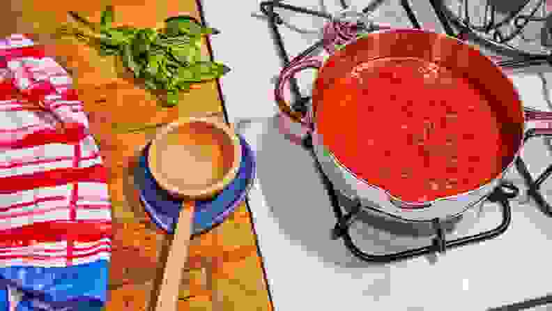 A pot of tomato sauce simmers on a gas cooktop with a wooden ladle to the left perched on a blue spoon rest.