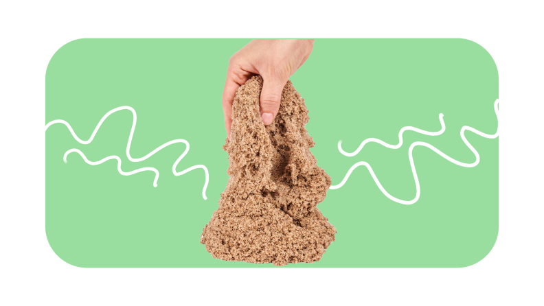 A hand playing with a pile of Kinetic Sand.