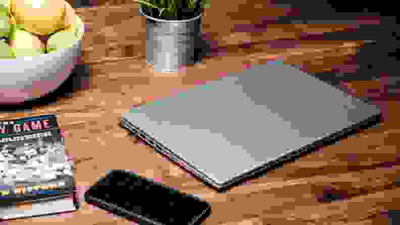 A closed laptop next to several items on wooden brown desk