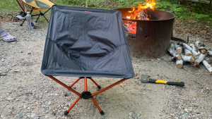 The REI Flexlite chair in front of a fire at a campsite.