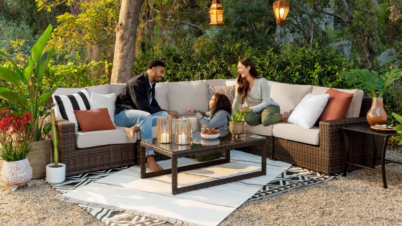 Family of three sitting outdoors on patio set from Yardbird.