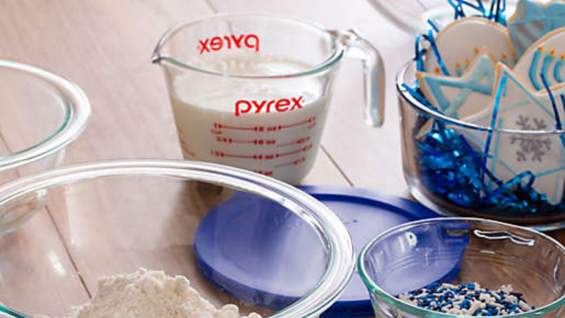 An image of a Pyrex measuring cup as seen through the rims of two glass bowls. The cup sits on top of a blue bowl lid.