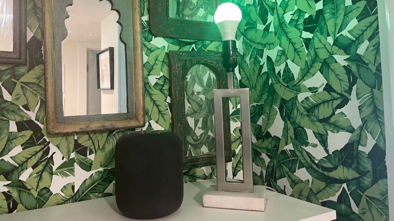 An Apple HomePod sits next to a smart light bulb