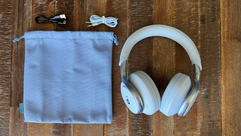 The Anker Soundcore Space One in sky blue alongside its carrying bag, USB-C cable, and 3.5 millimeter cable on a wooden table.