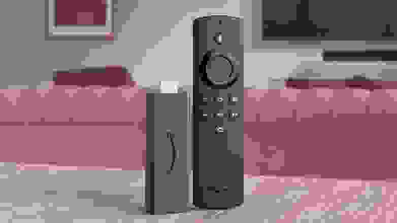 The Amazon Fire Stick Lite, which is a bare bones remote and streaming device in one, standing on a table.