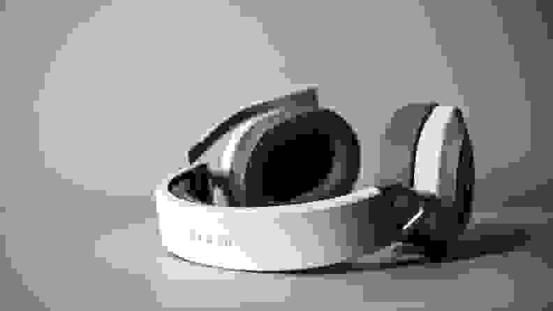 A white pair of headphones sits on a surface.
