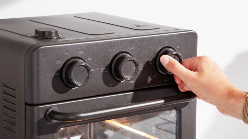 Person adjusting one of the three black knobs on the Wonder Oven.