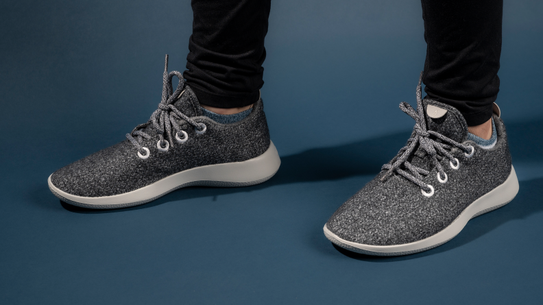 A woman's feet wearing a pair of grey Wool Runners against a dark blue backdrop.