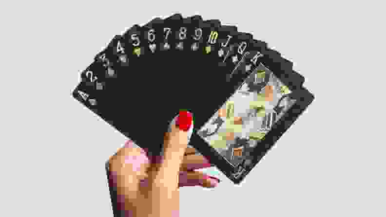 A hand with nails painted holds several Bierdorf playing cards spread out like a fan.