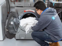 A person loading towels into a washing machine.