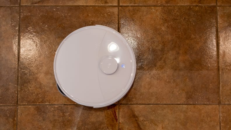 A round robot vacuum on a tile floor
