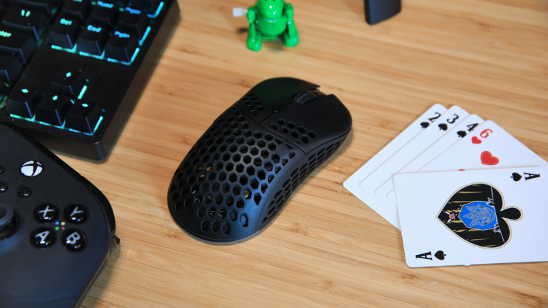 The Monoprice Dark Matter Hyper-K wireless mouse next to a stack of playing cards, an Xbox remote, and keyboard.