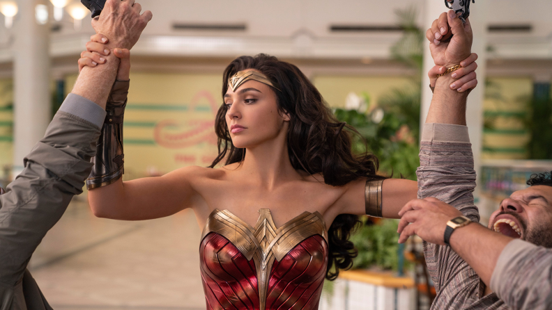 Gal Gadot as Wonder Woman defending herself against two attackers in Wonder Woman 1984.