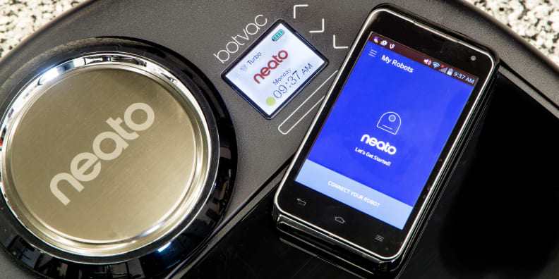 Phone sitting next to a robot vacuum.