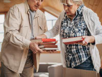Senior couple organizing books into box at home.