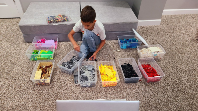 Small child sitting on floor surrounded by colorful assembly blocks.