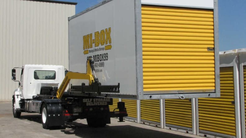 A portable container box being loaded onto the back of a truck