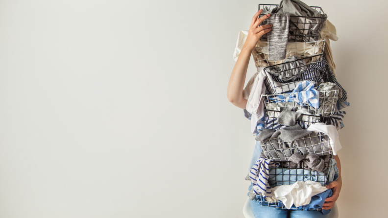 A person clutches baskets of laundry.