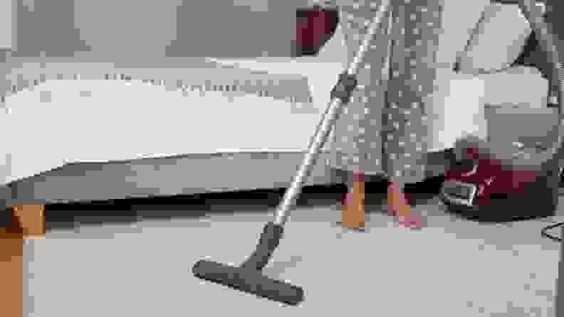 a woman in pajamas vacuums the rug in her room