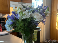 A blue, white, and purple bouquet of flowers on a kitchen counter.