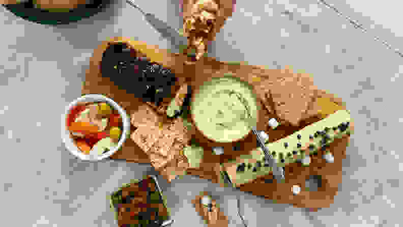 Hand spreading butter on baguette slice, next to a butter board.