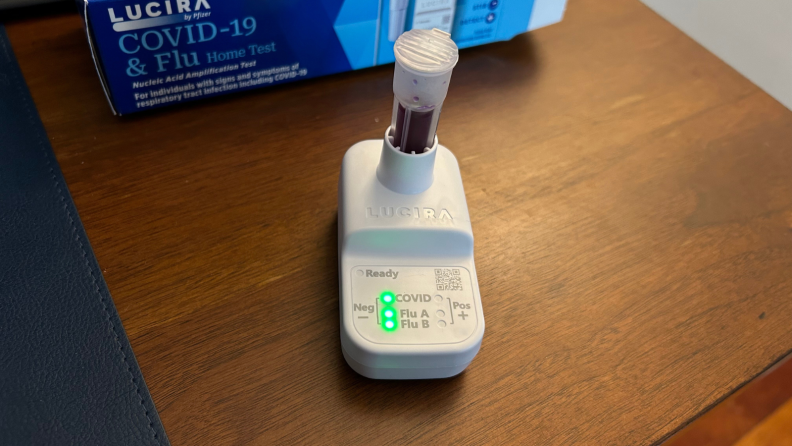 A vile filled with purple liquid attached to a test kit with illuminated results.