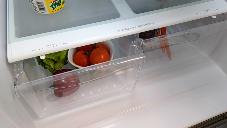 Tomatoes and a pepper sit in a crisper drawer