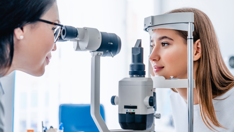 Woman at optometrist office getting her eyes examined by female doctor.