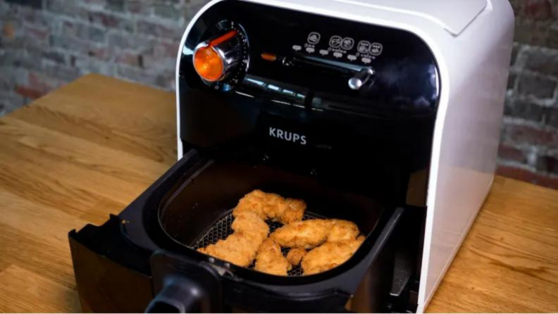 Close up of an air fryer with chicken fingers in the basket.