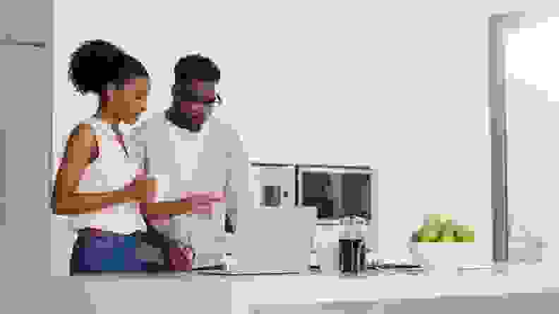 Couple looking at computer screening, standing at kitchen island