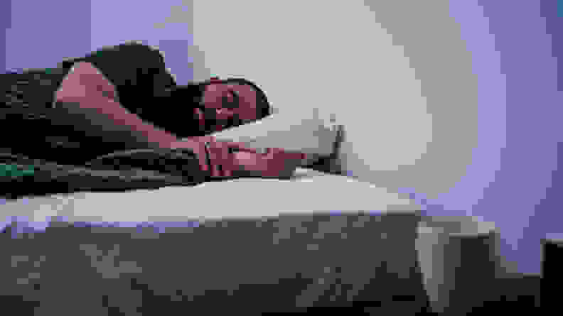 一名男子盖着床单睡在Awara床垫上