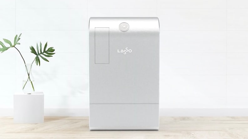 A large silver machine is on display in a minimalist office environment. This is a Lasso recycling machine.