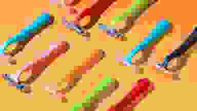 Two rows of colorful razors lay atop an orange background.