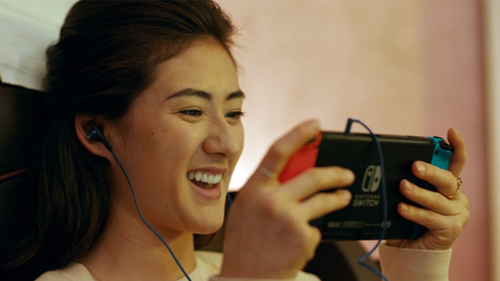 Image of a woman playing a Nintendo Switch with headphones in her ears
