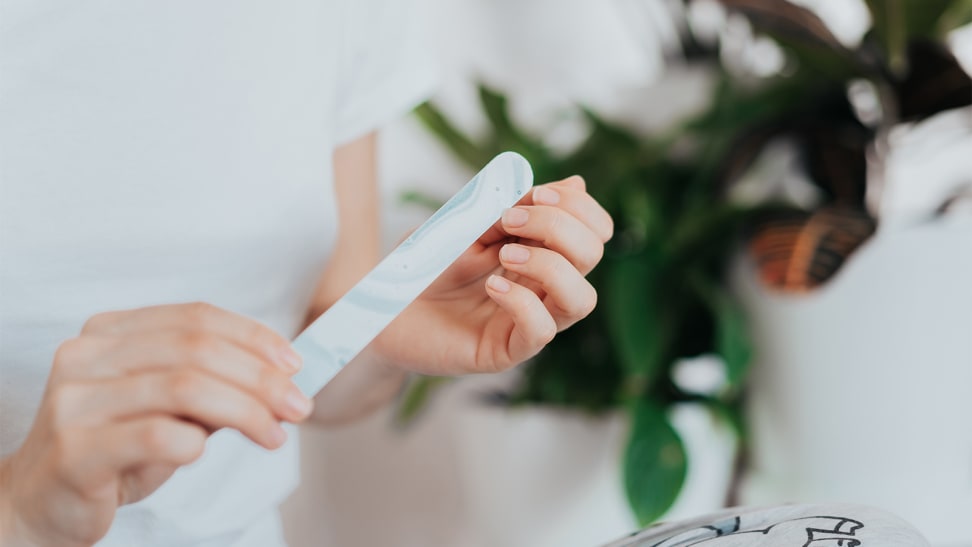 A closeup on a person holding a nail file up to their fingernails.