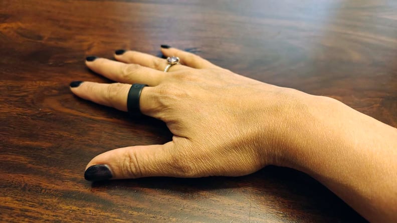 Circular Ring Slim and a wedding ring on fingers of a hand on a wooden table