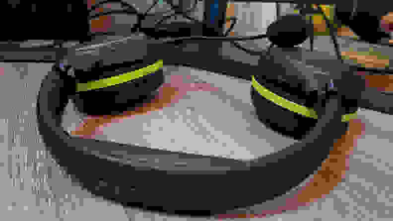 A gaming headset rests on a desktop with the earphones facing down.