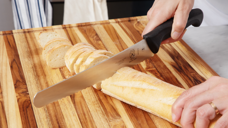 Hand using Mercer bread knife to slice into a baguette