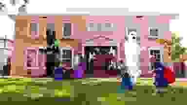 A house with 4 Halloween inflatables on the lawn and two children running