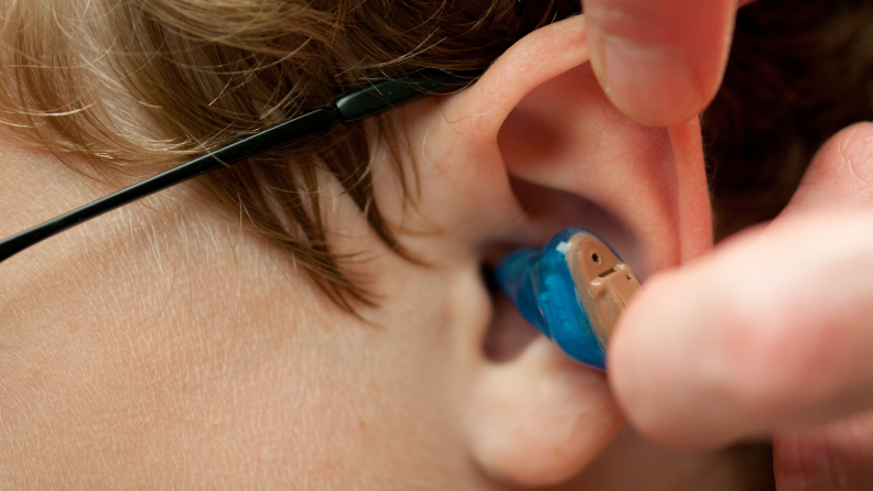 Close-up of a blue hearing aid in an ear