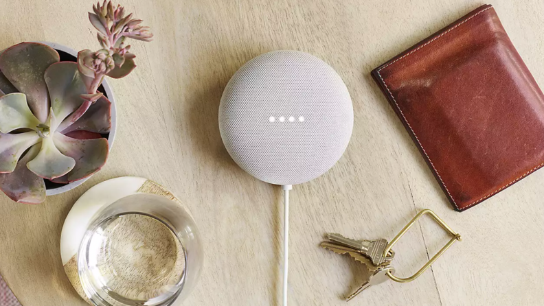 A Google Nest Mini sits on a table filled with items.