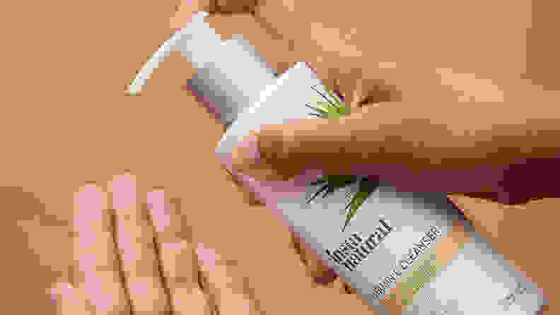 A person is holding out their hand palm side up and preparing to pump the InstaNatural Vitamin C Cleanser into it using their other hand.