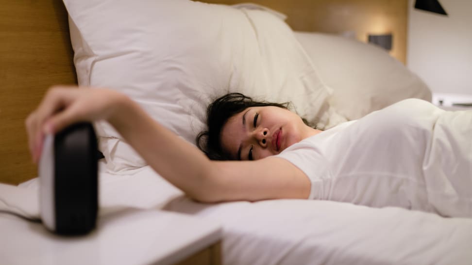 Woman groggily hits alarm near bed