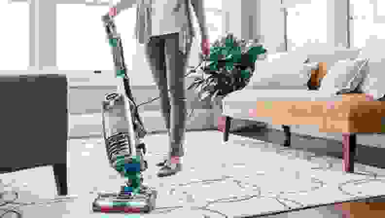 A woman vacuuming her carpet in the living room.