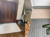 On left, Grid-patterned Heymat doormat in lime candycane color on top of wooden floorboards next to coat hook inside of home. On right, Grid-patterned Heymat doormat in lime candycane color on wooden deck outdoors in front of exterior of door.