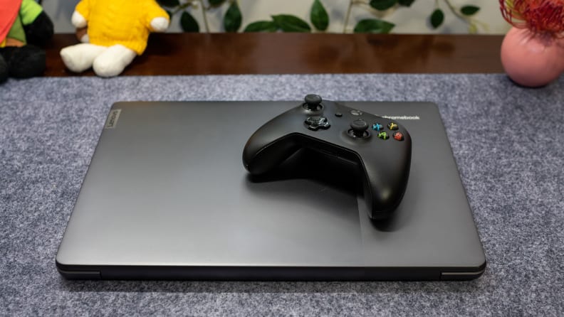 A closed Lenovo Ideapad Gaming Chromebook with gaming controller resting atop it.