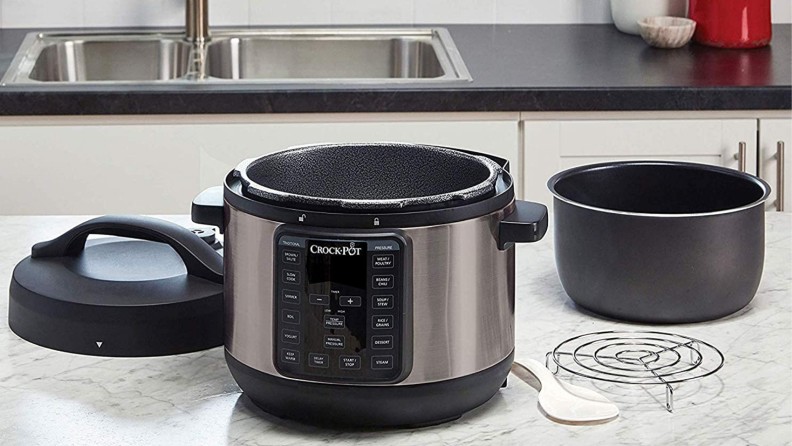 缸盖快车快速发行版6-QUART多炊具位于厨房柜台上，凭借盖子，蒸锅和内锅等配件。