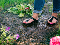 Girl wearing waterproof Birkenstock sandals stands in a garden.